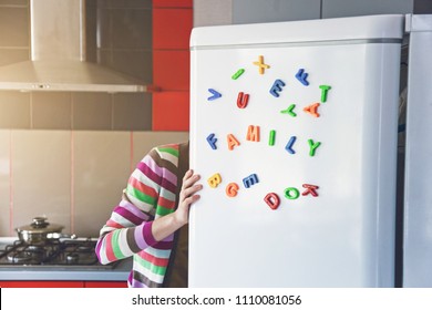 Woman Looking In Open Fridge With Family Letters On Door. Cooking For Children And Husband Concept