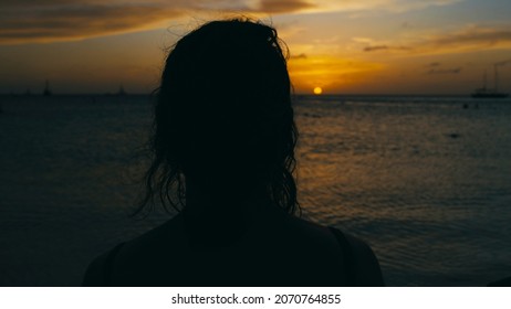 Woman Looking Out Over The Ocean On A Tropical Beach In Deep Contemplation