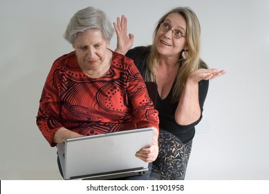 Woman Looking Over Her Elderly Mother's Shoulder While The Older Lady Is Working On A Laptop