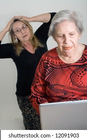 Woman Looking Over Her Elderly Mother's Shoulder While The Older Lady Is Working On A Laptop