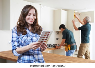 Woman Looking At Paint Chart In New Kitchen