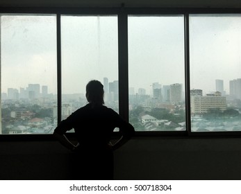 A Woman Looking The Rain Falling Through  Window And City View.