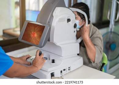 Woman looking at refractometer eye test machine in ophthalmology.Expert is taking pictures of the retina.