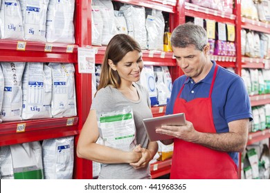 Woman Looking At Salesman Using Digital Tablet In Pet Store