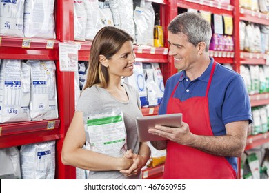 Woman Looking At Salesman Using Tablet Computer In Pet Store