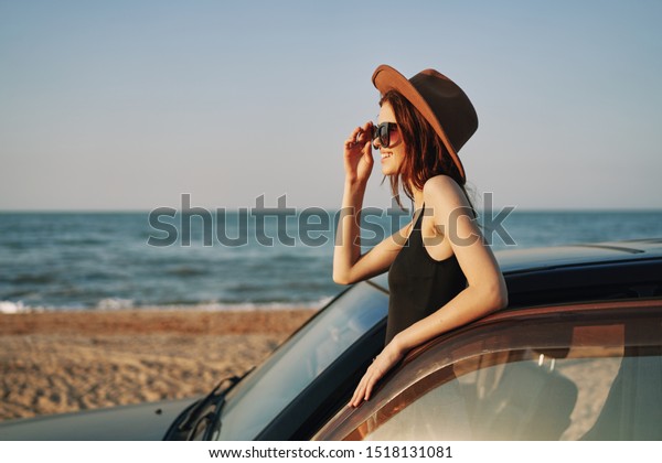 woman looking at\
the sea in a car with a\
hat