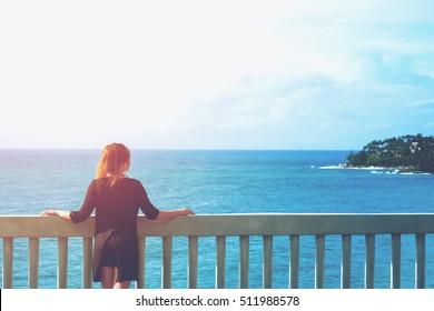 A woman looking to the sea in front of the beautiful ocean sky and island view