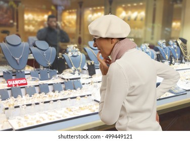 Woman looking to showcase or shop window. Shopping woman chooses jewelry in store