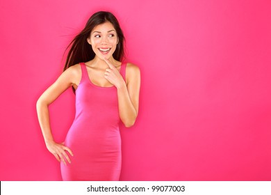 Woman Looking To The Side Excited Thinking On Pink Background. Beautiful Asian Woman Portrait In Dress Smiling Fresh Happy. Pretty Mixed Race Caucasian / Chinese Asian Female Fashion Model Brunette.
