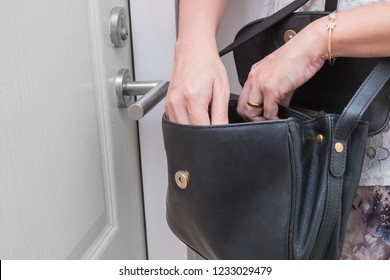 Woman looking for something such as keys in her handbag in front of her apartment