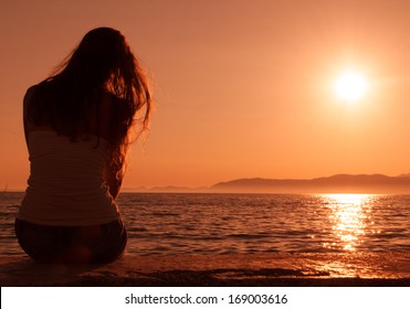 woman looking at the sunset on the beach