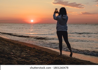 woman looking at sunset standing at sea beach