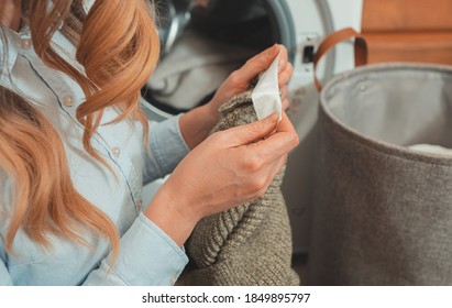 Woman looking at the tag on the clothes before loading clothes into washing machine.