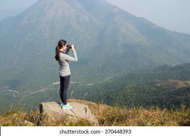 Woman looking though binoculars at mountain