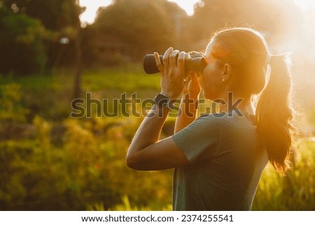 Woman looking through binoculars at the nature of the Pantanal in Brazil. Beautiful sunset view on the lake