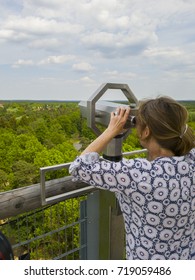 Woman looking through binoculars on a lookout tower