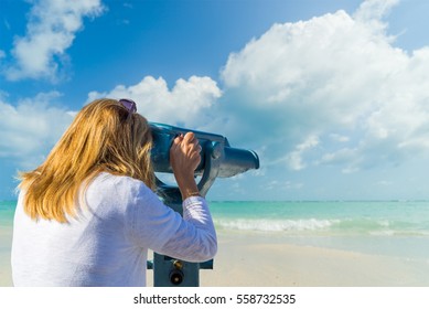 Woman Looking Through Binoculars Or Telescope On The Tropical  Beach