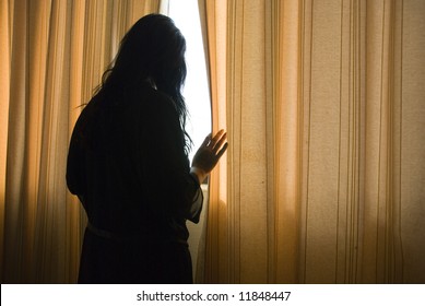 Woman Looking Through Curtains.