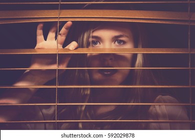 Woman Looking Through Window Blinds