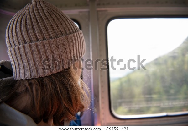 Woman looking through window while traveling in\
overhead cable car