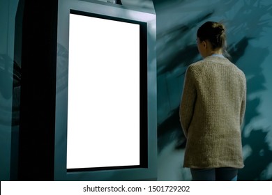 Woman Looking At Vertical Blank Digital Interactive White Display Kiosk At Dark Room Of Exhibition, Museum, Low Light Illumination. Mock Up, Copyspace, Isolated, White Screen, Technology Concept