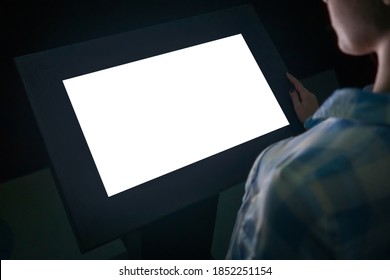 Woman Looking At White Blank Interactive Touchscreen Display Of Electronic Multimedia Kiosk In Dark Room Of Technology Exhibition - Close Up View. Mock Up, Copyspace, Template And Futuristic Concept