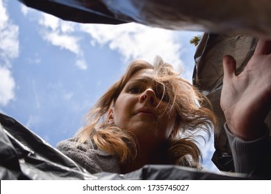 A Woman Looks In A Black Plastic Bag. Look In The Trash. Search For Missing In Trash. Woman Looking In The Garbage Something. A Hungry Man In Garbage Container.