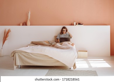 Woman looks at her laptop in the bedroom while working. Working from home because of quarantine