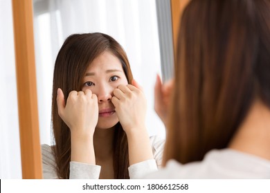 A woman looks at her skin condition in a mirror.