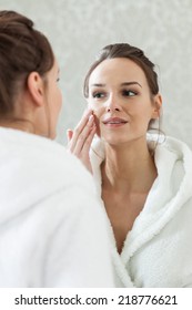 Woman looks at herself in the mirror in spa