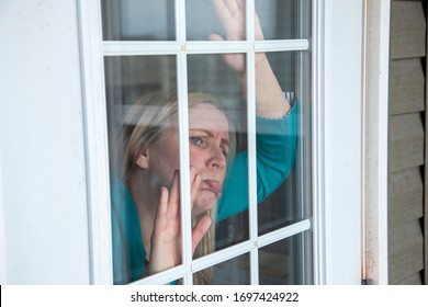 Woman Looks Longingly Outside Her Front Window While Stuck Inside 