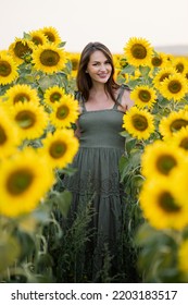 Woman Looks With Smiling And Happy Expression Standing Against Blooming Sunflower Field. Lady Enjoys Spending Weekends In Countryside Closeup