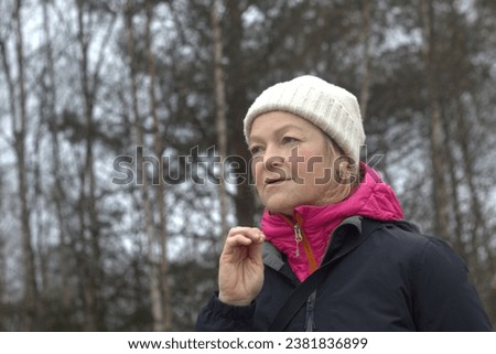 Woman looks up and thinks. Woman in autumn forest with hat and jacket.