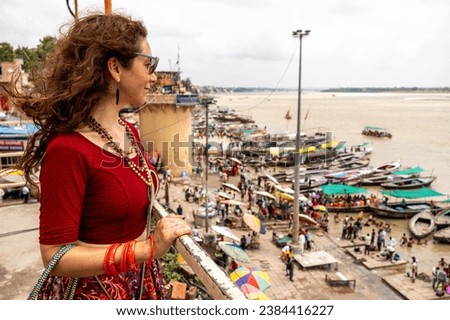 Woman looks the view of the Ganges with its boats, people and sacred water of Varanasi in India