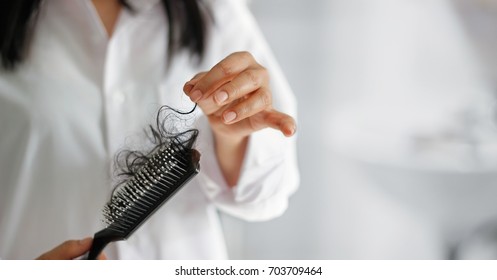 woman losing hair on hairbrush in hand, soft focus