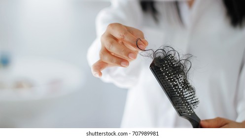 Woman losing hair on hairbrush in hand, soft focus