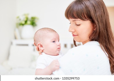 Woman as a loving mother holds her newborn baby tenderly in her arms