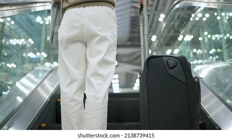 Woman With Luggage Standing On The Escalator In The International Airport Terminal. Going To Counter For Check In Before Go Aboard. Transportation And New Normal Concept