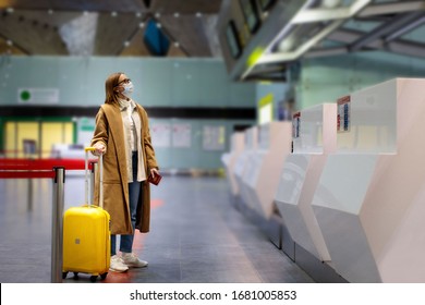 Woman with luggage stands at almost empty check-in counters at the airport terminal due to coronavirus pandemicCovid-19 outbreak travel restrictions. Flight cancellation.Quarantine all over the world - Shutterstock ID 1681005853