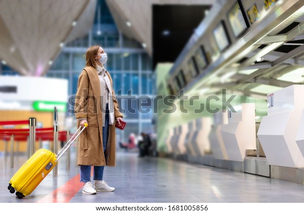 Woman with luggage stands at almost empty check-in\
counters at the airport terminal due to coronavirus\
pandemicCovid-19 outbreak travel restrictions. Flight\
cancellation.Quarantine all over the\
world