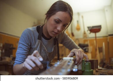 woman luthier is tuning a classic guitar in her musical instrument workshop