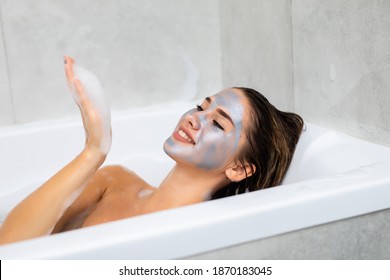 Woman lying in bathtub with a sheet mask on her face - Powered by Shutterstock