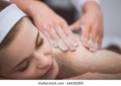 Woman lying at beautician's during exfoliating sugar scrub massage