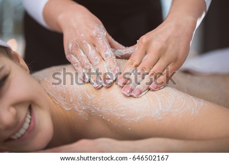 Woman lying at beautician's during exfoliating sugar scrub massage