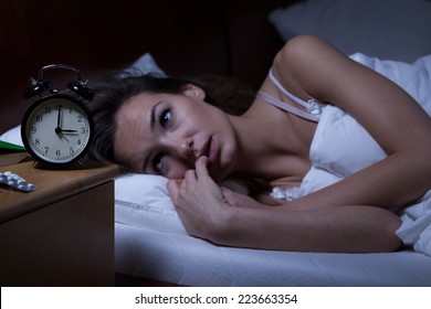Woman lying in bed sleepless at night - Shutterstock ID 223663354