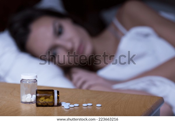 Woman lying in bed,
taking sleeping pills