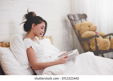 Woman lying in bed while reading a book - Shutterstock ID 1911521443