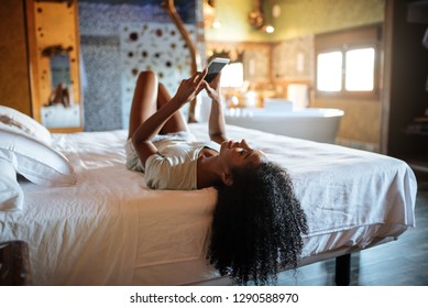 Woman Lying Down On The Bed With A Mobile Phone