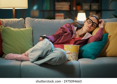 Woman lying down on the sofa at home and watching TV