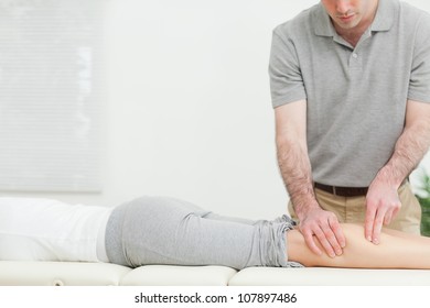 Frau, die vorwärts liegt, während eine Physiotherapeutin ihr Bein in einem Raum massiert